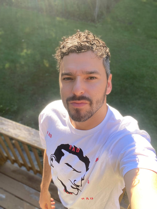 Curly haired man selfie image wearing a white BAD tshirt