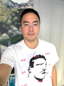 Asian man with glasses wearing a white BAD tshirt